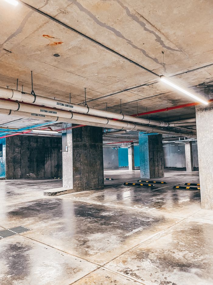 Spacious underground parking garage with concrete pillars and bright lighting.
