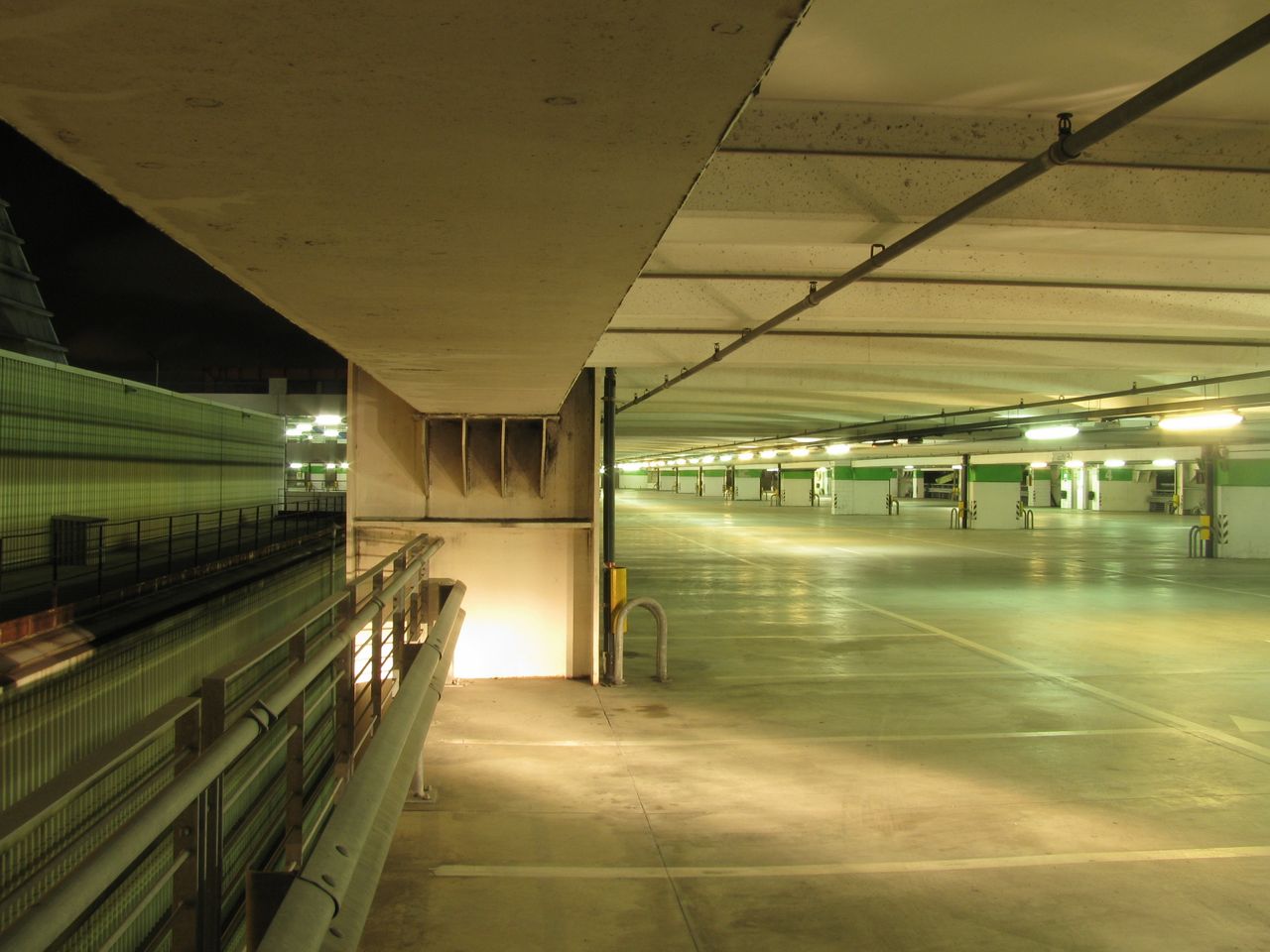 Empty upper floor of a well-lit urban parking garage at night.