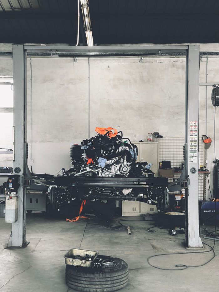 Interior view of a car repair workshop in Beijing, China featuring a vehicle lift and engine.