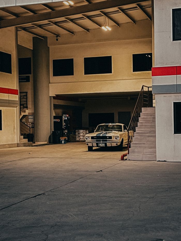 Vintage car parked in an industrial garage with minimalistic design elements.